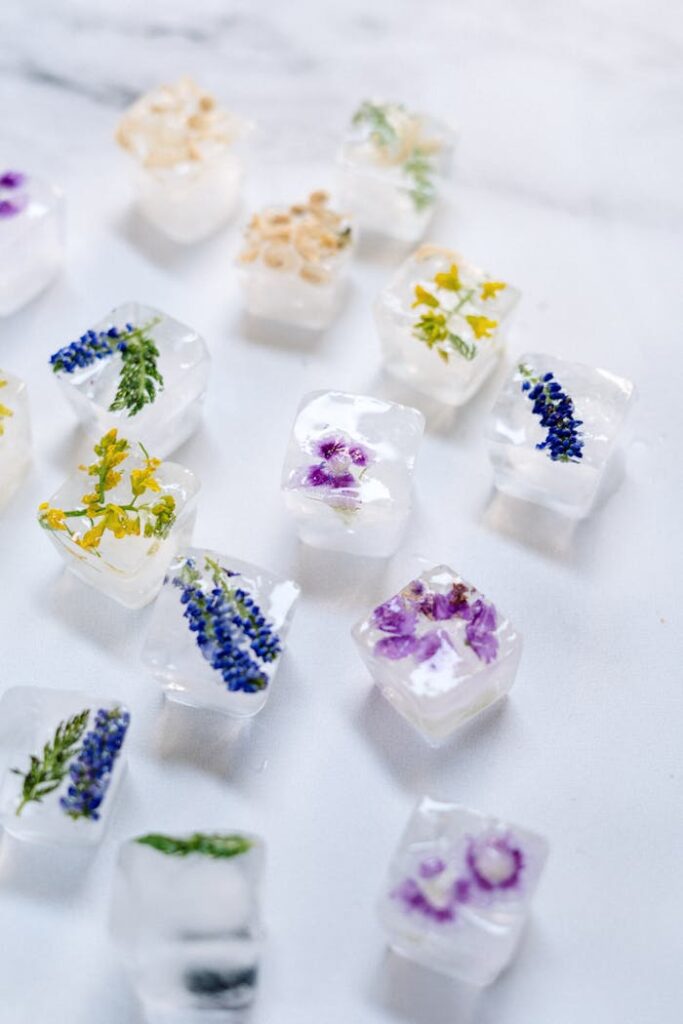 Close-up view of floral ice cubes with embedded flowers on a marble surface, perfect for refreshing drinks.